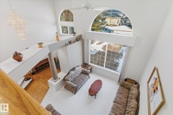 Living area featuring high ceilings, large windows with arch-top elements, and a decorative chandelier - 