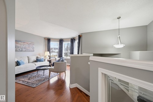 Living area featuring a bay window, wood-finish flooring, light gray wall tones, and a contemporary pendant light fixture - 21 Escada Close, St. Albert, AB - Indoor