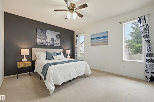 Spacious room featuring a dark accent wall, light wall finishes, and multiple windows - 21 Escada Close, St. Albert, AB - Indoor Photo Showing Bedroom