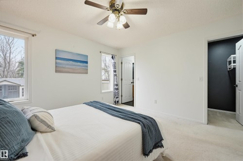 Bright bedroom featuring white walls, a ceiling fan with light fixture, carpet flooring, and two windows providing natural light - 21 Escada Close, St. Albert, AB - Indoor Photo Showing Bedroom