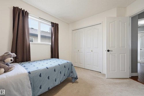 Carpeted interior room featuring a double-pane window with white trim, a built-in closet with bi-fold doors, and a paneled interior door with matte black hardware - 21 Escada Close, St. Albert, AB - Indoor Photo Showing Bedroom