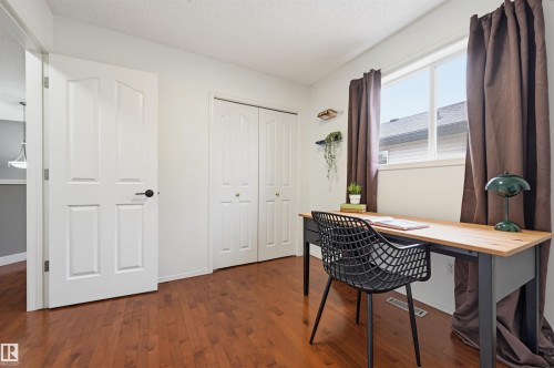 Hardwood-finish flooring enhancing a versatile room featuring white walls, a window with natural light, and bi-fold closet doors - 21 Escada Close, St. Albert, AB - Indoor Photo Showing Office