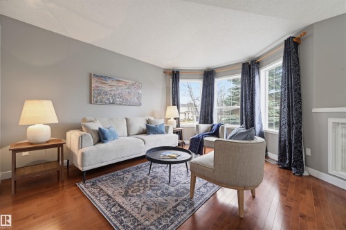 Living space featuring warm wood-finish flooring, light gray wall paint, and a bay window configuration - 21 Escada Close, St. Albert, AB - Indoor Photo Showing Living Room