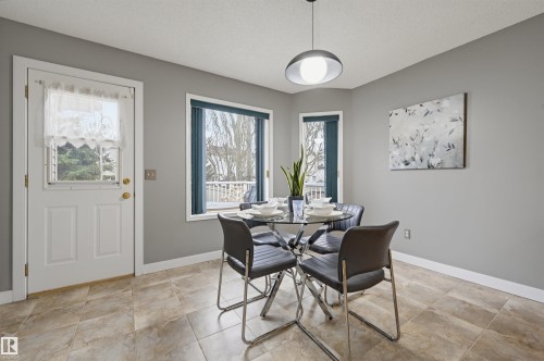 Dining area with light gray walls, two large windows, a white door, and textured tile flooring - 21 Escada Close, St. Albert, AB - Indoor Photo Showing Dining Room