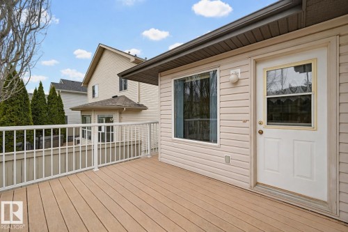 Expansive outdoor deck featuring wood-finish flooring, white railing, and a side entry door with a window - 21 Escada Close, St. Albert, AB - Outdoor With Deck Patio Veranda With Exterior