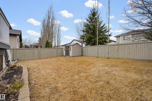 Expansive backyard featuring a full wood fence, a detached storage shed, and a raised garden bed with stone edging - 21 Escada Close, St. Albert, AB - Outdoor