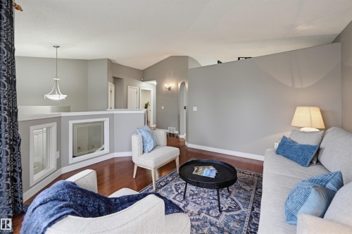 Open concept living area featuring wood-finish flooring, a decorative half-wall with inset windows, and a vaulted ceiling - 21 Escada Close, St. Albert, AB - Indoor