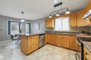 Spacious kitchen featuring light wood cabinetry, stone countertops, a tile backsplash, and stainless steel appliances - 21 Escada Close, St. Albert, AB  - Indoor Photo Showing Kitchen With Double Sink 