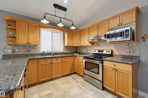 Kitchen featuring abundant light wood cabinetry, stone-finish countertops, stainless steel appliances, a tiled backsplash, and recessed lighting - 21 Escada Close, St. Albert, AB - Indoor Photo Showing Kitchen