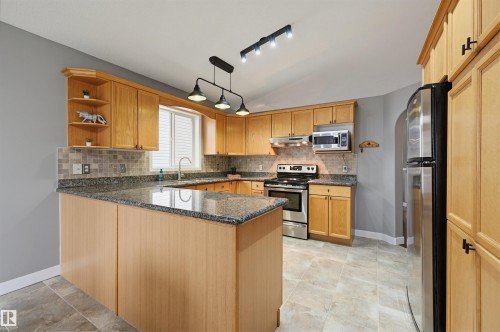 Bright kitchen featuring light wood cabinetry, granite countertops, stainless steel appliances, and a tiled backsplash - 21 Escada Close, St. Albert, AB - Indoor Photo Showing Kitchen With Stainless Steel Kitchen