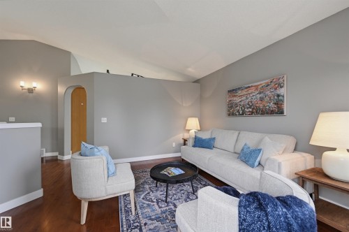 Living area featuring vaulted ceilings, wood-finish flooring, an arched doorway, and sconce lighting - 21 Escada Close, St. Albert, AB - Indoor Photo Showing Living Room