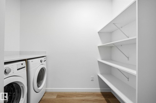 Dedicated laundry area featuring a white countertop, wood-finish flooring, and built-in shelving - 202 7459 May Common, Edmonton, AB - Indoor Photo Showing Laundry Room