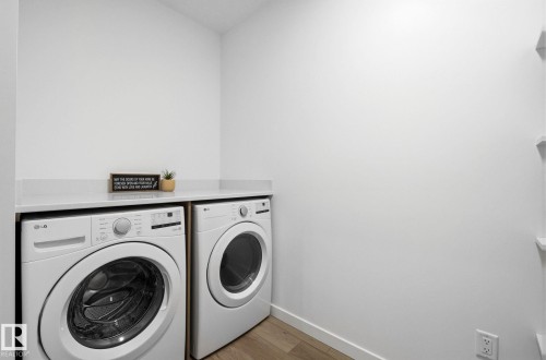 Laundry area featuring front-load washer and dryer, a light-colored countertop, and wood-finish flooring - 202 7459 May Common, Edmonton, AB - Indoor Photo Showing Laundry Room