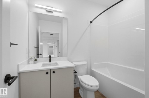 Modern bathroom featuring a single vanity with stone-finish countertop, undermount sink, and black fixtures - 202 7459 May Common, Edmonton, AB - Indoor Photo Showing Bathroom