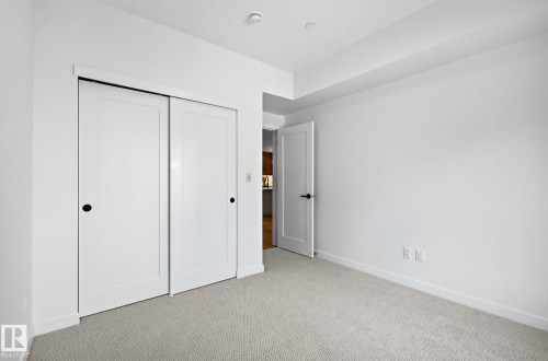 Neutral-toned carpet flooring complementing white walls and trim - 202 7459 May Common, Edmonton, AB - Indoor Photo Showing Other Room