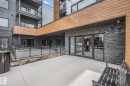 Modern multi-story building entrance featuring dark brick and light wood-finish siding - 202 7459 May Common, Edmonton, AB  - Outdoor With Balcony With Exterior 