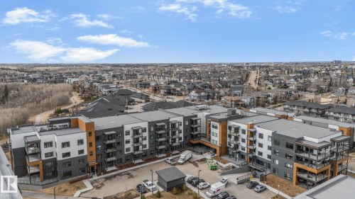 Multi-story residential building featuring a contemporary design with grey, white, and wood-toned paneling - 202 7459 May Common, Edmonton, AB - Outdoor With View