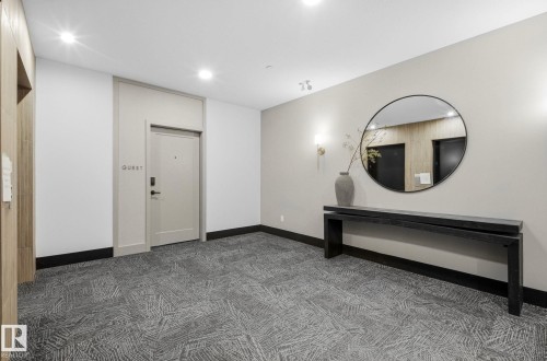 Hallway featuring patterned carpet flooring, recessed lighting, and a console table with wall sconces - 202 7459 May Common, Edmonton, AB - Indoor Photo Showing Other Room