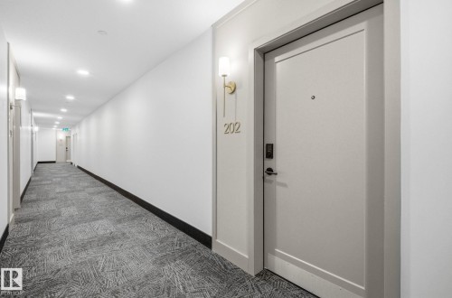 Entry door with modern keyless access system, brushed brass sconce, and unit numbering - 202 7459 May Common, Edmonton, AB - Indoor Photo Showing Other Room