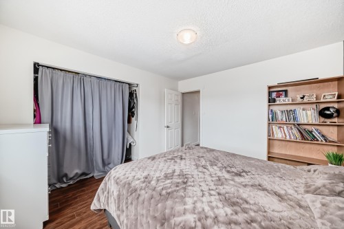 Bedroom featuring wood-finish flooring, a built-in closet with curtain enclosure, a light wood built-in shelving unit, and an overhead flush-mount light fixture - 75 Amberly Court, Edmonton, AB - Indoor Photo Showing Bedroom