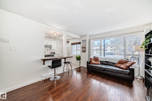 Open-concept living area featuring wood-finish flooring and a pass-through kitchen with a breakfast bar - 75 Amberly Court, Edmonton, AB - Indoor Photo Showing Living Room