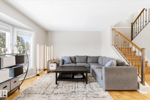 Living area with wood-finish flooring and a staircase featuring a wooden handrail and wrought-iron balusters - 70 Stirling Road, Edmonton, AB - Indoor Photo Showing Living Room