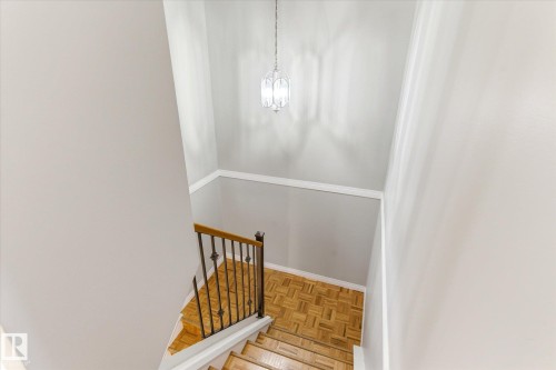 Staircase landing featuring wood-finish flooring, a decorative metal and wood-finish railing, and a pendant light fixture - 70 Stirling Road, Edmonton, AB - Indoor Photo Showing Other Room