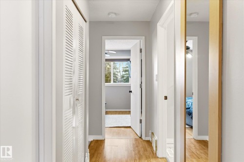 Hallway featuring wood-finish flooring, light grey wall paint, white trim, and white louvered bifold doors - 70 Stirling Road, Edmonton, AB - Indoor Photo Showing Other Room