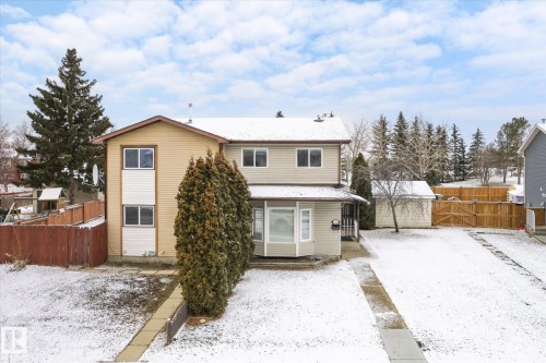 Two-story residence featuring light-colored siding, a covered front entry, and a front yard with a concrete pathway and driveway - 70 Stirling Road, Edmonton, AB - Outdoor