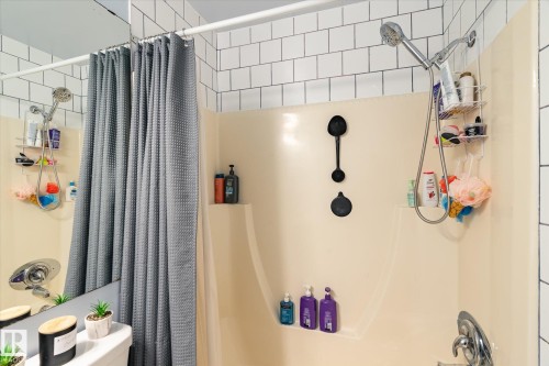 Shower enclosure featuring a built-in shelf, white subway tile surround, and chrome fixtures - 70 Stirling Road, Edmonton, AB - Indoor Photo Showing Bathroom