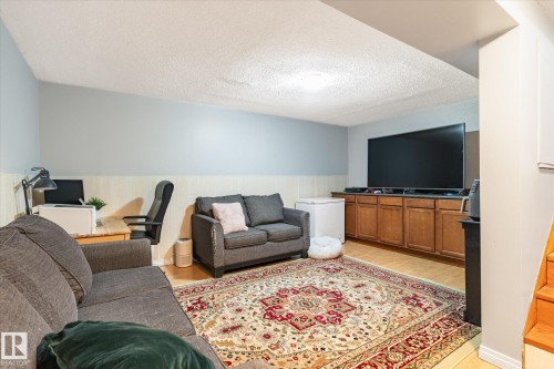 Finished recreation space featuring wood-finish flooring, wainscoting, and a built-in entertainment console with cabinetry - 70 Stirling Road, Edmonton, AB - Indoor Photo Showing Other Room