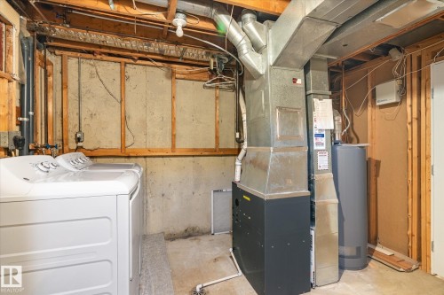 Laundry area featuring a top-load washing machine, a furnace with visible ductwork, and a water heater - 70 Stirling Road, Edmonton, AB - Indoor Photo Showing Basement
