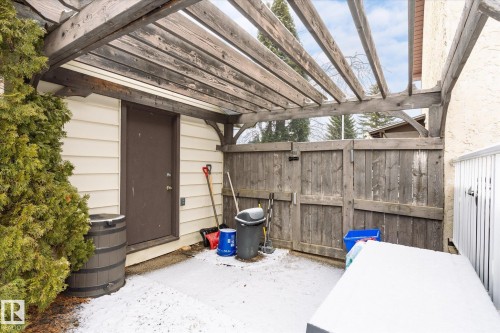 Fenced patio featuring a wood pergola, wood privacy fencing, and exterior entry door - 70 Stirling Road, Edmonton, AB - Outdoor With Exterior