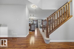 Hardwood-finish flooring extending through the main level, complemented by a wood-railed staircase with carpeted treads - 