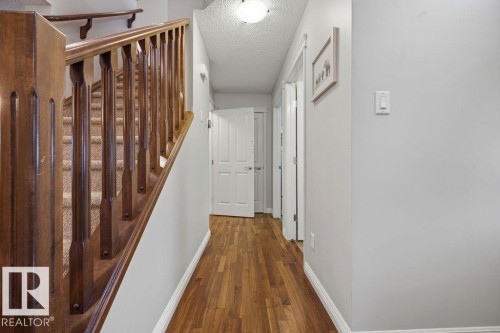 Hardwood-finish flooring extending through a hallway with white paneled doors, light grey wall paint, and white trim - 1613 Kerr Road, Edmonton, AB - Indoor Photo Showing Other Room