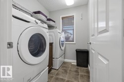 Dedicated laundry area featuring dual front-load appliances, tiled flooring, and a window with blinds - 