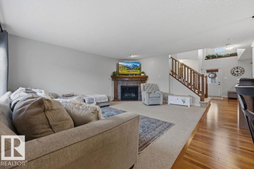 Expansive living space featuring a central fireplace with a wooden mantel and dark tile surround - 1613 Kerr Road, Edmonton, AB - Indoor Photo Showing Living Room With Fireplace
