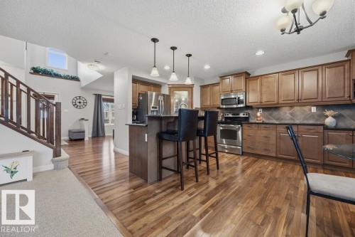 Kitchen featuring wood-finish flooring, dark stone countertops, stainless steel appliances, and a tile backsplash - 1613 Kerr Road, Edmonton, AB - Indoor Photo Showing Kitchen With Upgraded Kitchen
