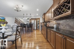Open-concept kitchen and dining area featuring wood-finish flooring, recessed lighting, and a built-in wine rack - 