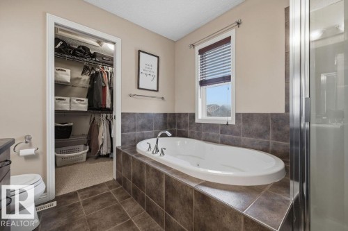 Soaking tub with chrome fixtures, tile surround, and a frosted window with horizontal blinds - 1613 Kerr Road, Edmonton, AB - Indoor Photo Showing Bathroom
