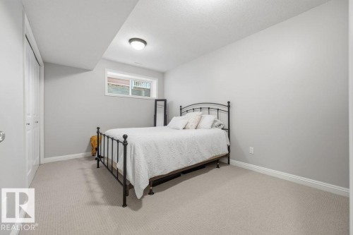 Carpeted room featuring a white window with a gridded insert, a flush-mount ceiling light, and white bi-fold closet doors - 1613 Kerr Road, Edmonton, AB - Indoor Photo Showing Bedroom