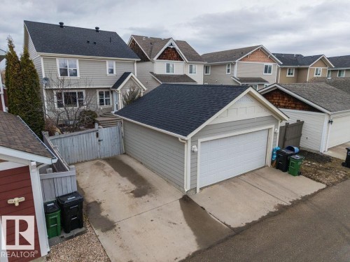 Detached garage featuring light gray siding, white trim, a dark shingle roof, and a panel garage door - 1613 Kerr Road, Edmonton, AB - Outdoor