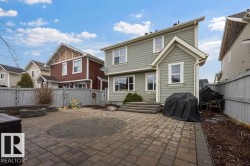 Spacious paver patio with circular inlay, featuring a stone fire pit and built-in stone benches - 