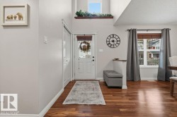 Entryway featuring wood-finish flooring, a white paneled entry door, and a built-in wall niche - 