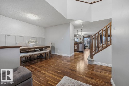 Rich wood-finish flooring extends through the main level, featuring a dining area with decorative wainscoting and a staircase with wood balusters - 1613 Kerr Road, Edmonton, AB - Indoor