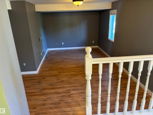 Spacious room featuring wood-finish flooring, dark wall paint, white trim, and a window for natural light - 5306 44 Street, Cold Lake, AB - Indoor Photo Showing Other Room