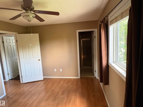 Wood-finish flooring, a ceiling fan with integrated lighting, and white trim work - 5306 44 Street, Cold Lake, AB - Indoor Photo Showing Other Room