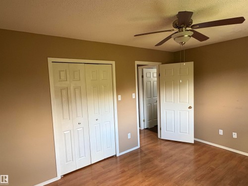 Wood-finish flooring, paneled doors, ceiling fan with integrated lighting, and neutral wall tones - 5306 44 Street, Cold Lake, AB - Indoor