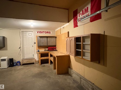 Garage with built-in workbench, wall-mounted storage cabinets, and slatwall paneling - 5306 44 Street, Cold Lake, AB - Indoor