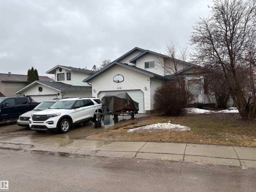 White siding exterior with an attached garage, featuring a basketball hoop - 5306 44 Street, Cold Lake, AB - Outdoor